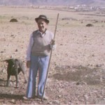 Pastor Majorero con su Lata, Perro Propio de la Isla de Fuerteventura conocido como Perro Bardino y Perro Majorero, y Ganado de Cabras al fondo en Las Parcelas - Foto de Antonio Cardona Sosa en su Libro 'Juegos y Deportes Vernáculos y Tradicionales Canarios (1995)' - Puerto Cabras y Del Rosario - Fuerteventura - Archivo Documental de la Federación de Salto del Pastor Canario (FSPC) - Archipiélago Canario (Años 80 ó 90 del Siglo XX).